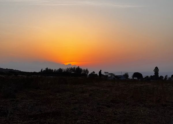 Sunrise over an open landscape with a solitary figure on the horizon, reflecting on the value of patience, perspective, and meaningful travel.