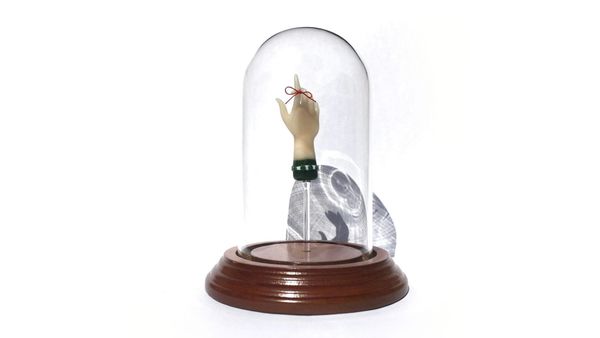 A hand with a green sleeve reaches made of borosilicate glass reaches upward with the index finger extended. A dainty red ribbon is tied around the index finger. Mounted in a glass cloche