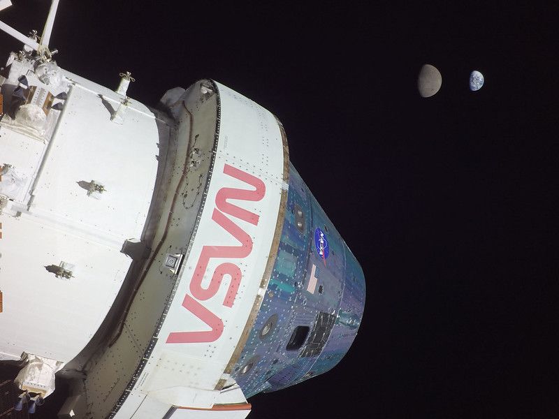 NASA’s uncrewed Orion spacecraft in the foreground, with the frickin' moon in front of Spaceship Earth in the background.