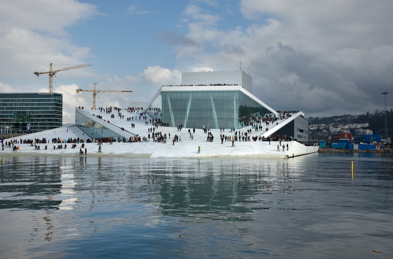 A bunch of nordic people walking around on the top of the Oslo Opera House