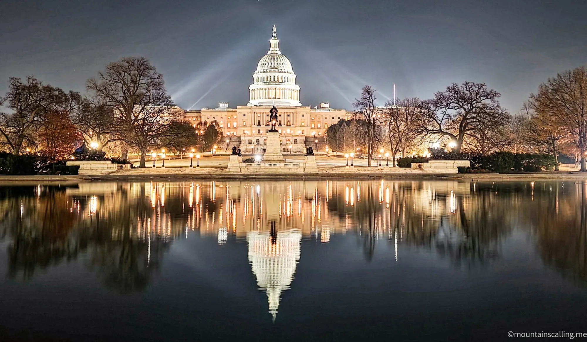US Capitol Building illuminated at night with dome and columns reflected in Capitol Reflecting Pool