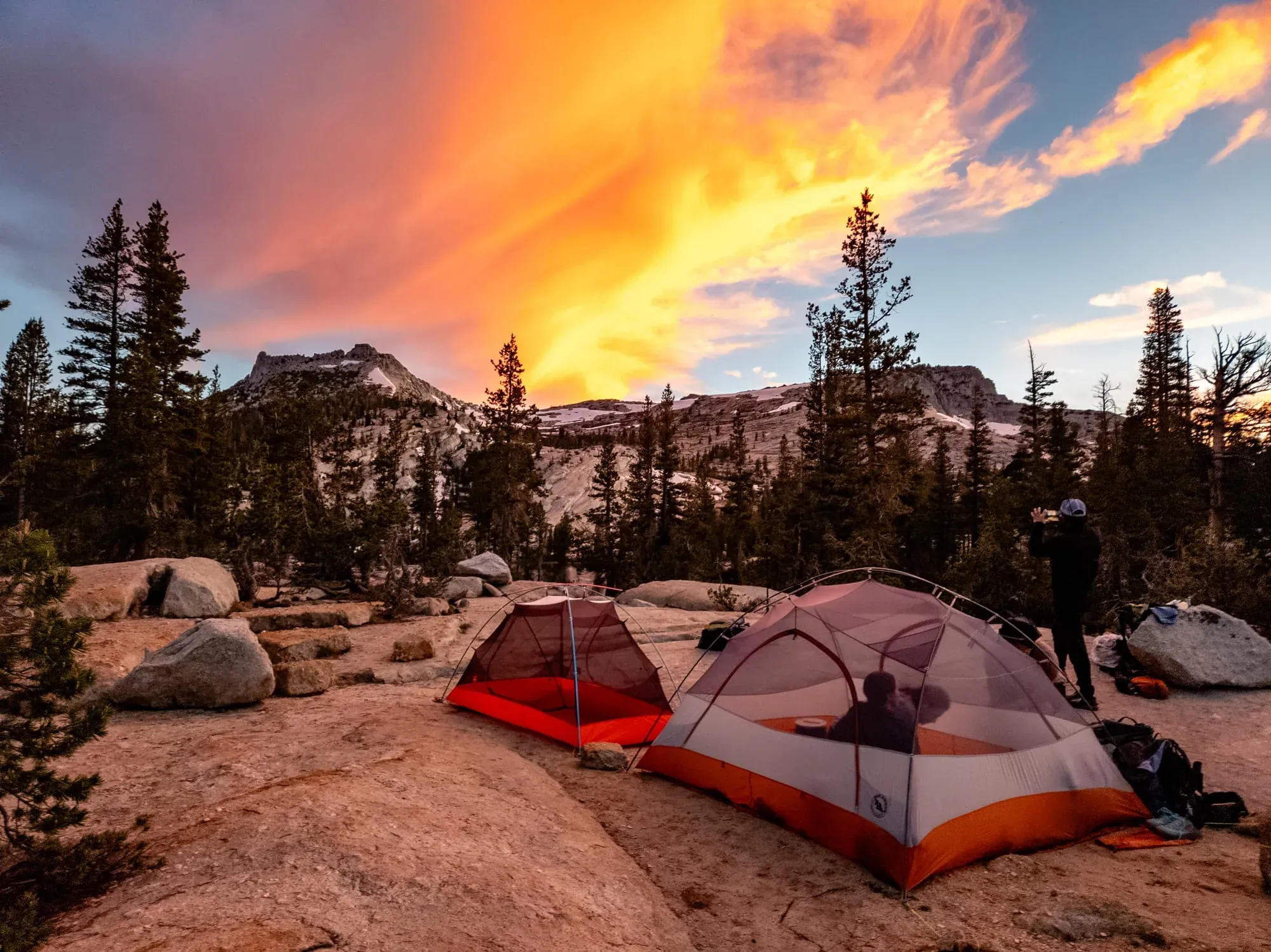 Backpacking tents set up on granite slabs at sunset during guided Yosemite wilderness trip with mountain views