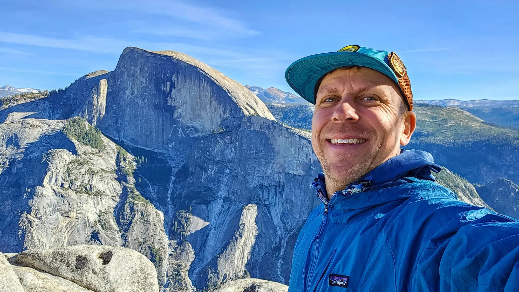 Yosemite guide Eric Kufrin taking selfie at Glacier Point overlook with Half Dome granite face behind him