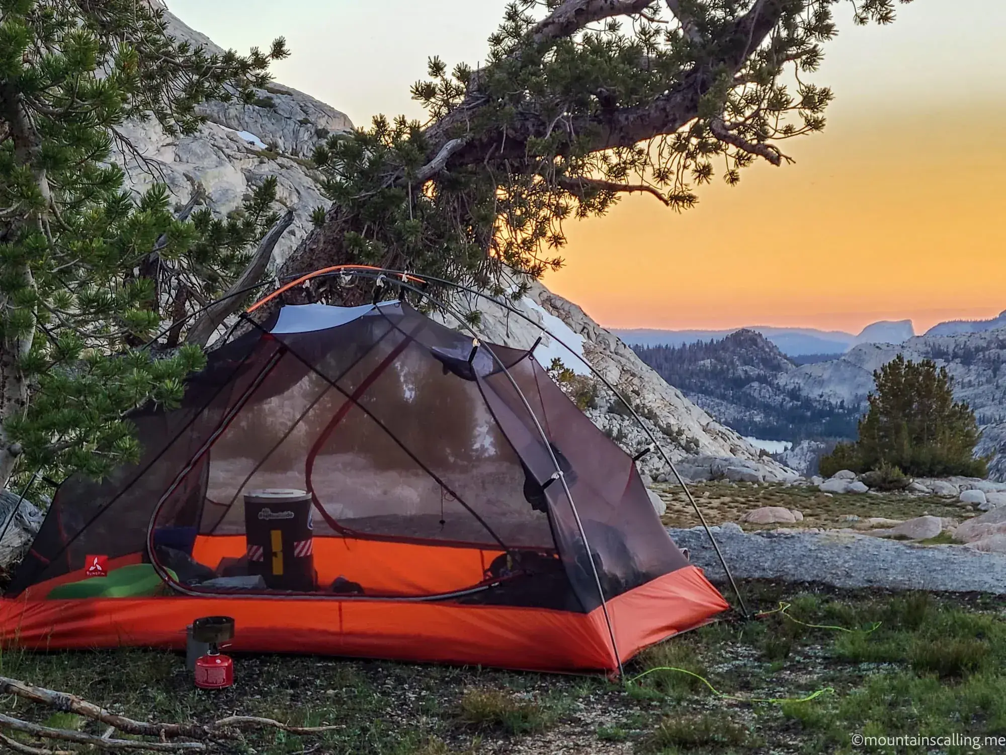 Illuminated backpacking tent at golden hour with Yosemite granite landscape during guided wilderness trip