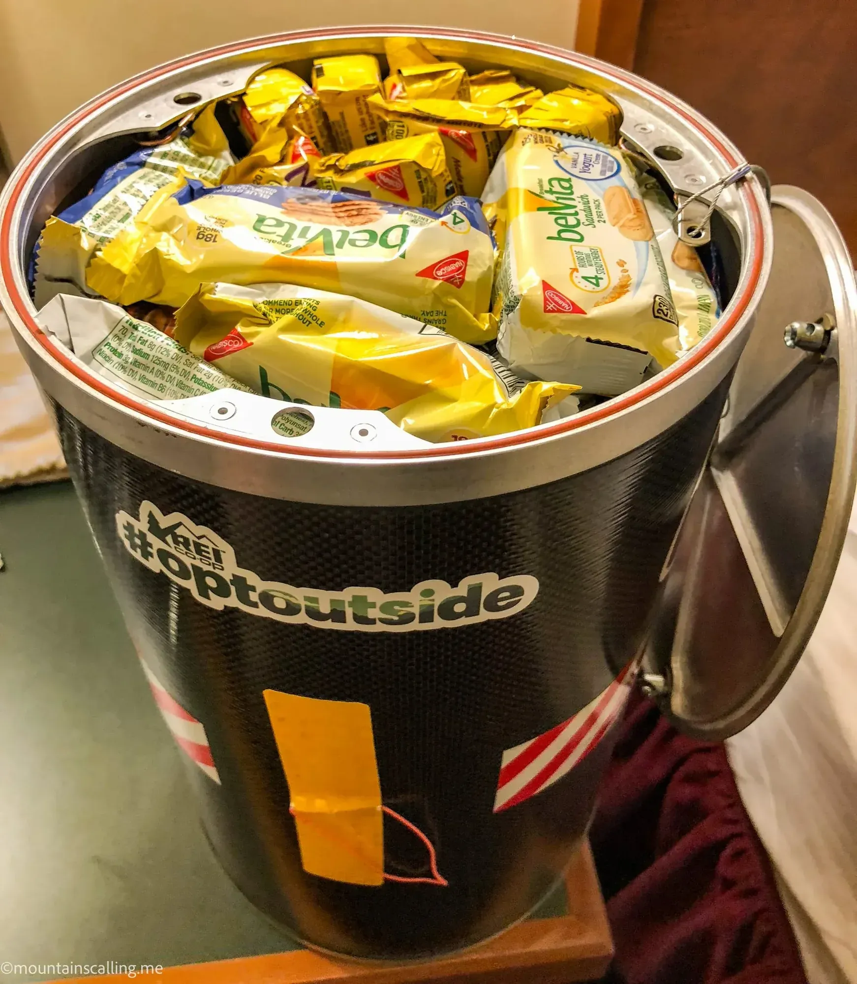 Packed bear canister filled with backpacking food packages and supplies for multi-day trip