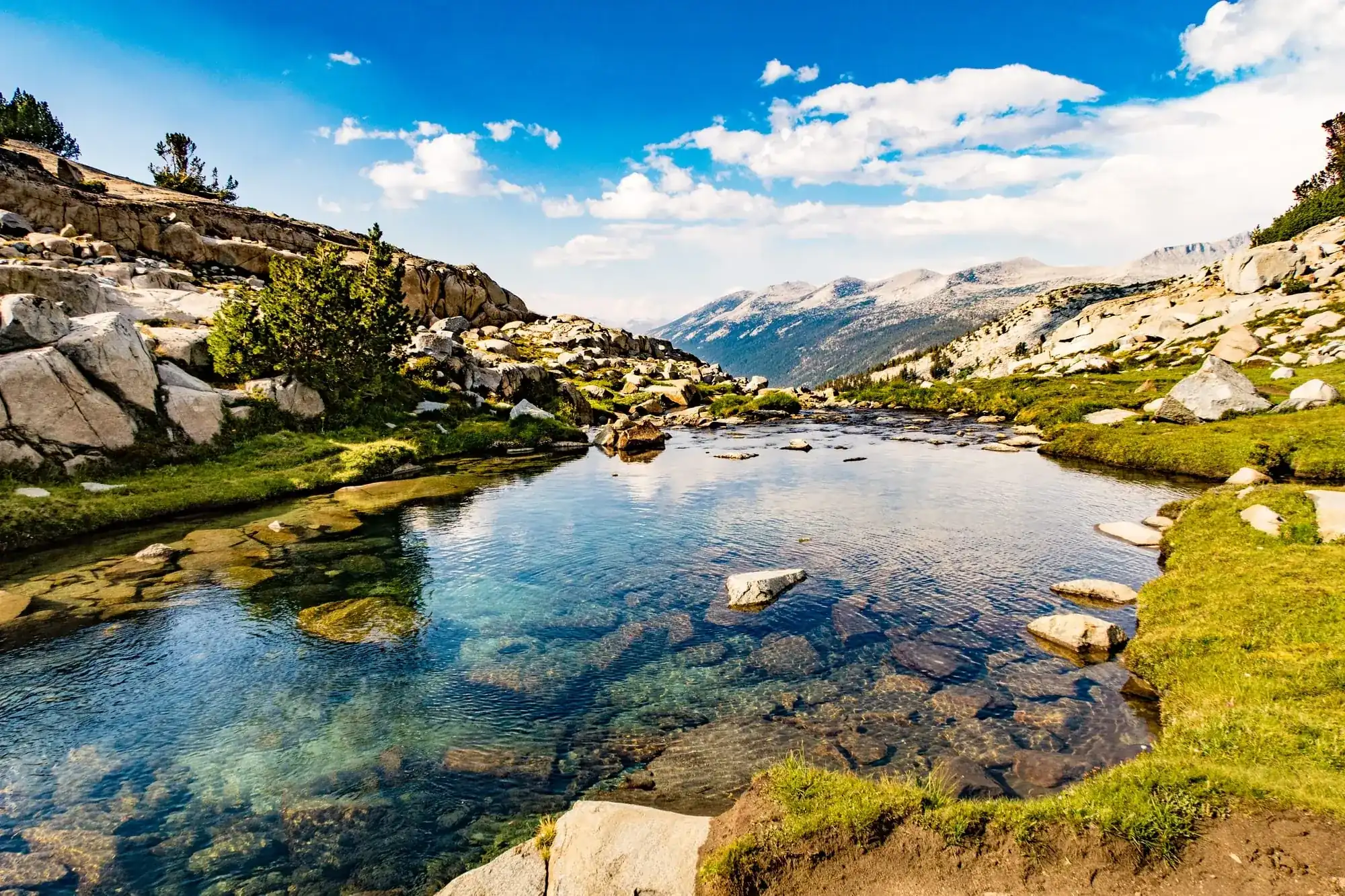 Crystal clear alpine lake surrounded by granite slabs and meadows in Yosemite's high country backcountry