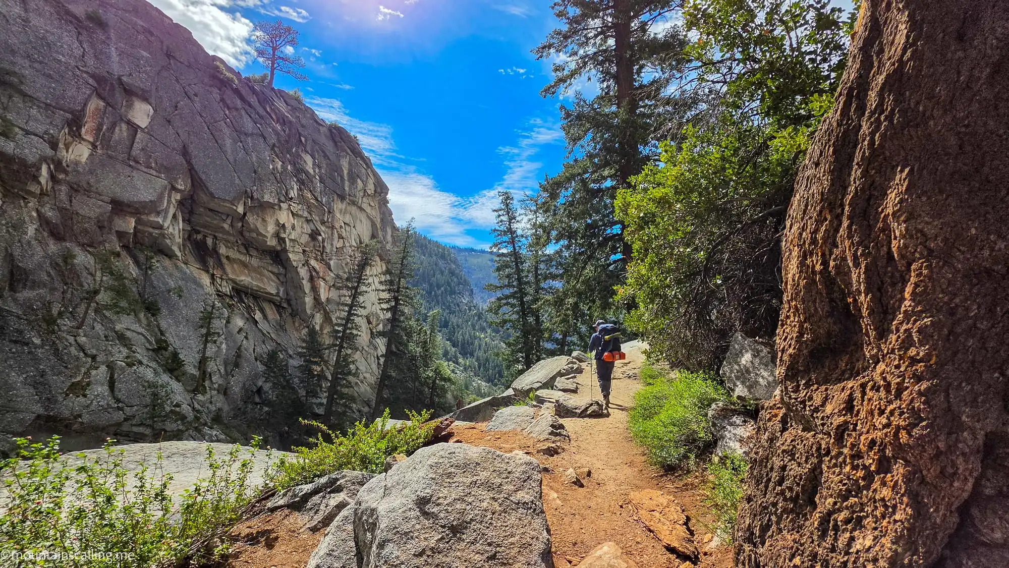 Hiker on maintained trail section of Clouds Rest route with granite cliffs and mountain backdrop