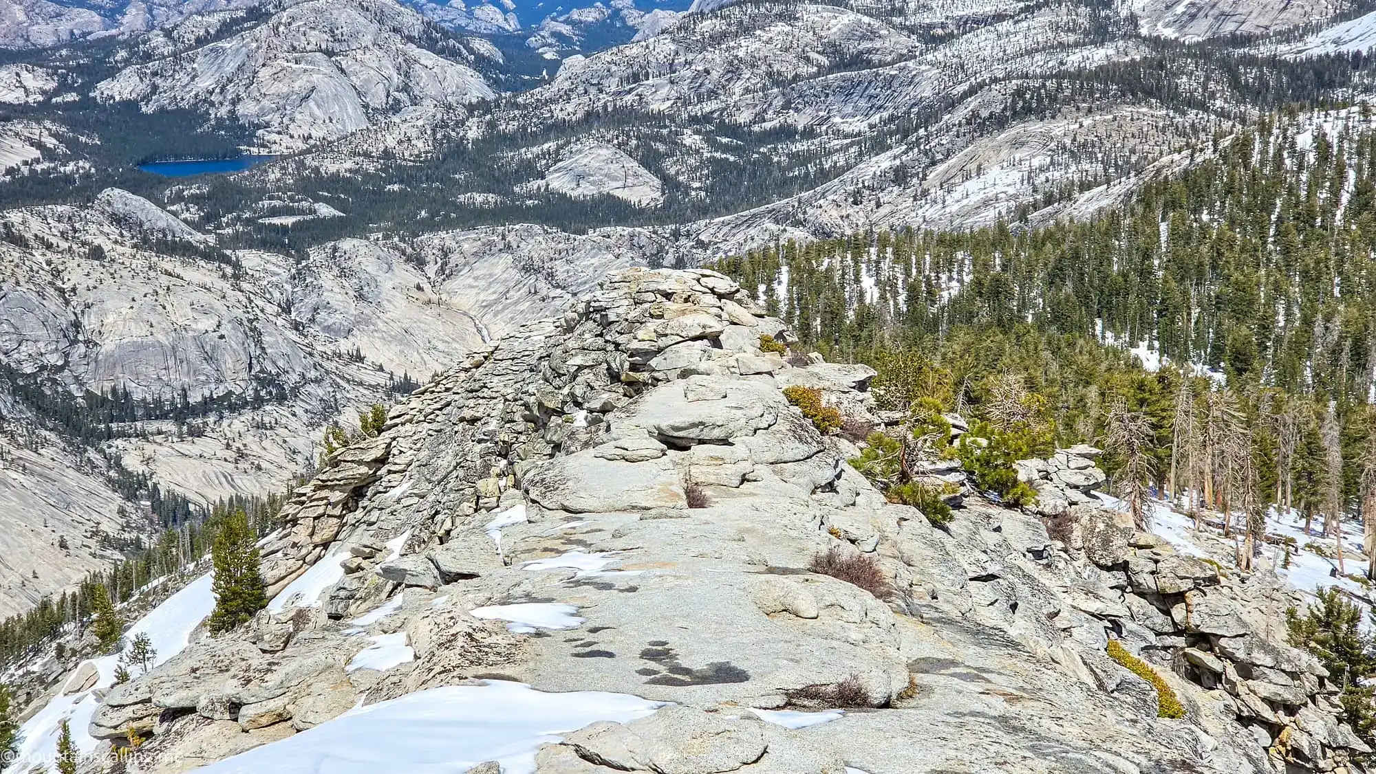 Layered granite formations and alpine lake views from Clouds Rest summit ridge in Yosemite wilderness