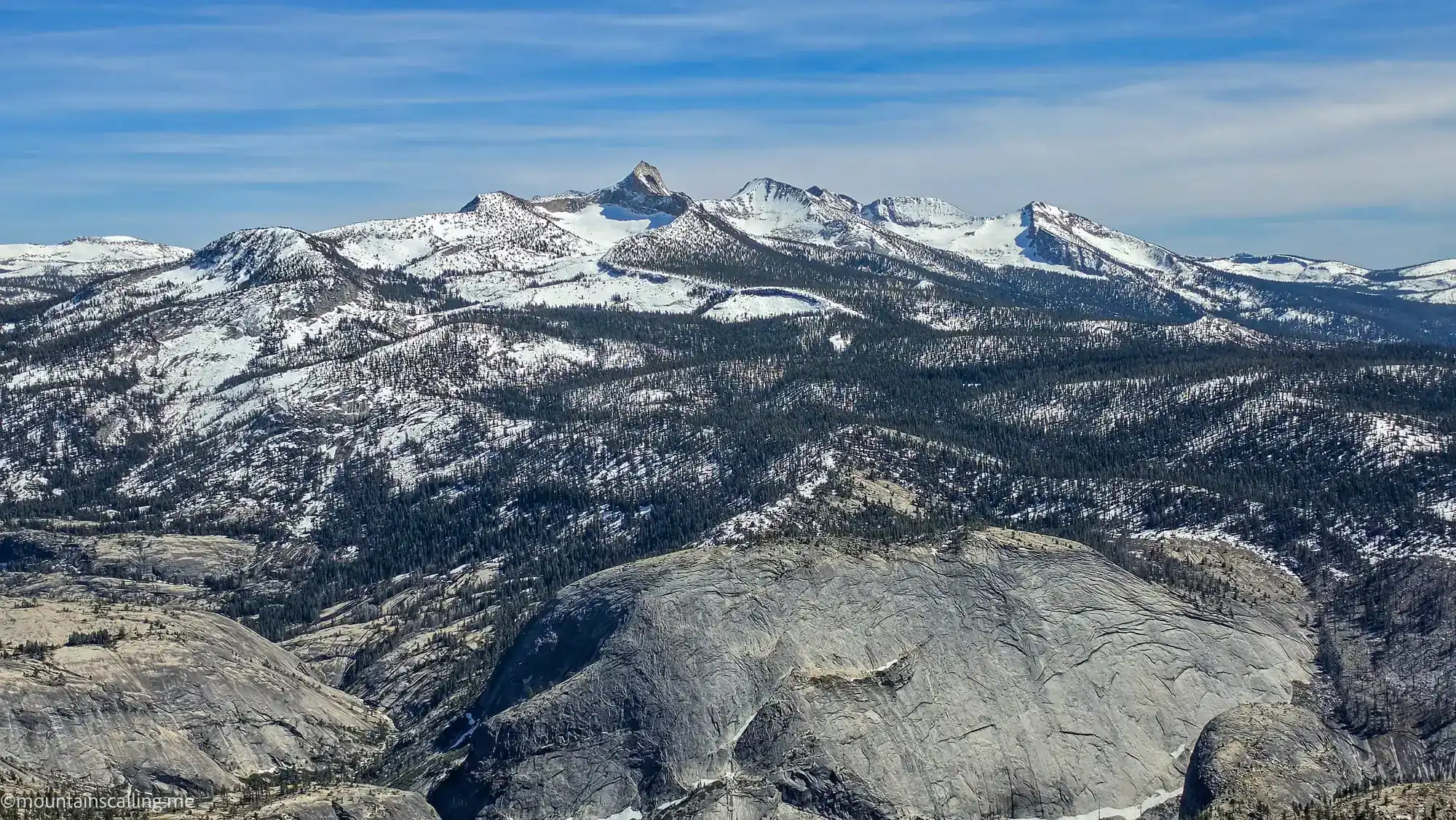 Snow-covered Sierra Nevada peaks viewed from Clouds Rest summit with granite domes in foreground