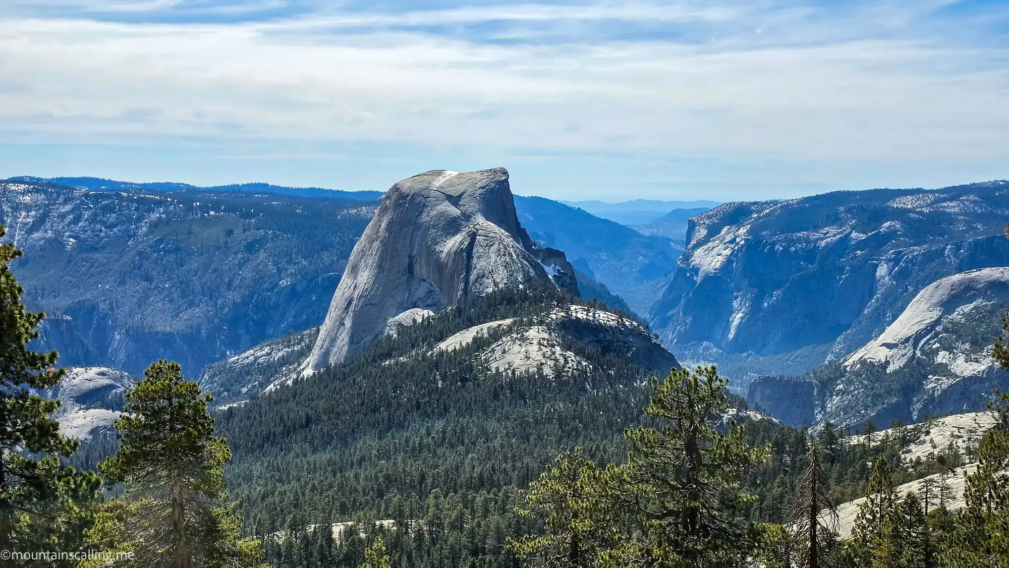 Half Dome's iconic granite face viewed from Clouds Rest trail in Yosemite, showing the distinctive steep cliff and surrounding Sierra Nevada peaks