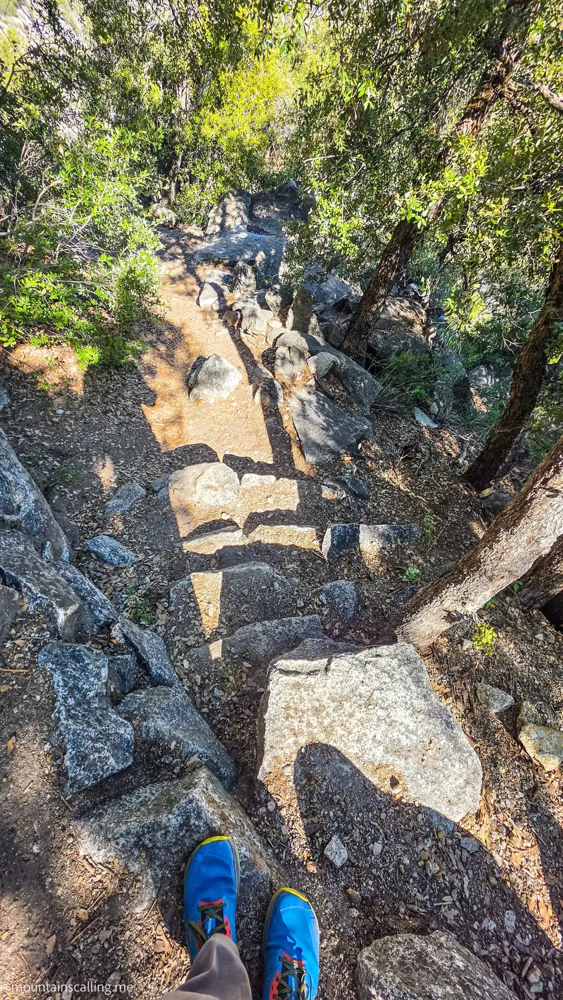 Steep rocky scramble section on OMG Point trail with loose granite boulders and blue hiking shoes visible