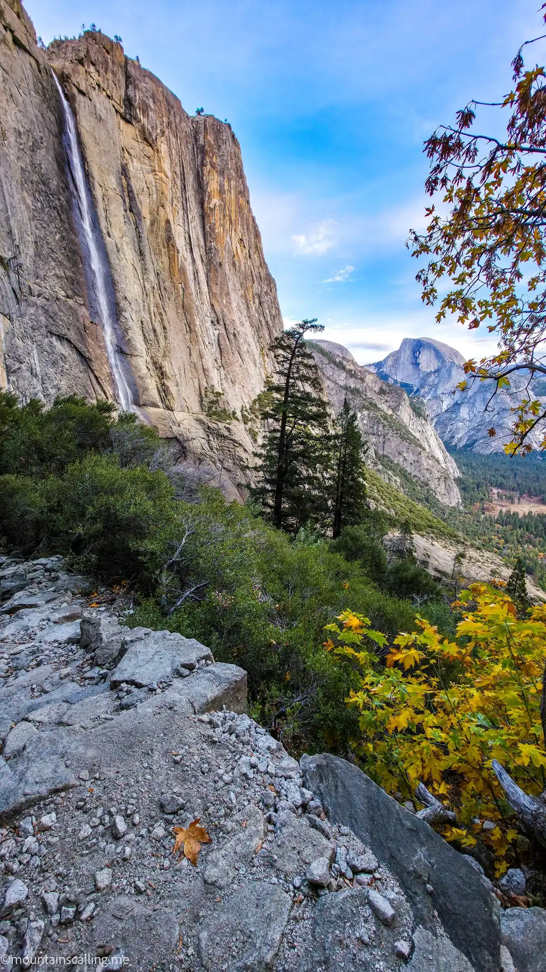 Upper Yosemite Falls waterfall and Half Dome granite peak viewed from Yosemite Falls Trail with autumn foliage