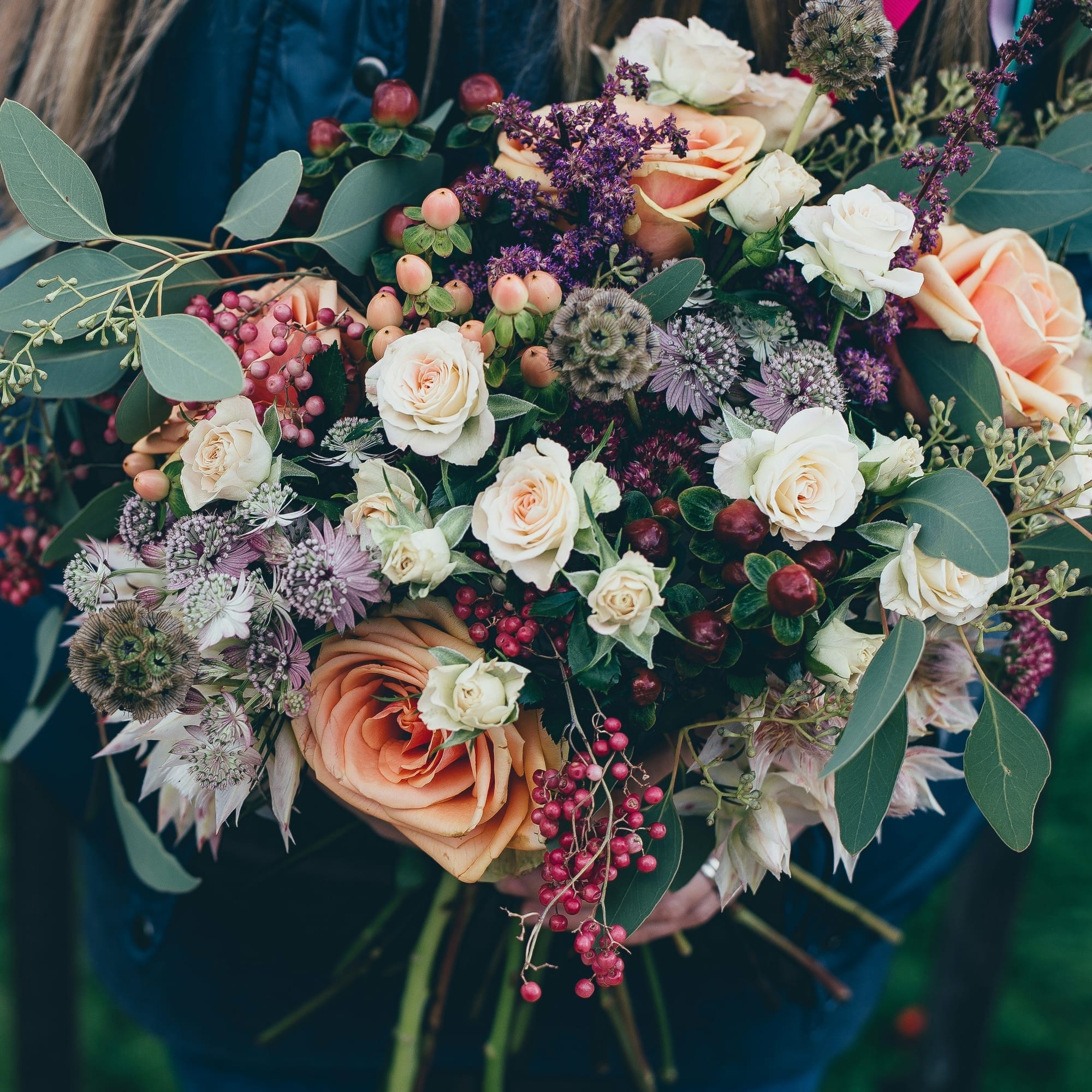 A bouquet of various flowers, leaves, and berries. 