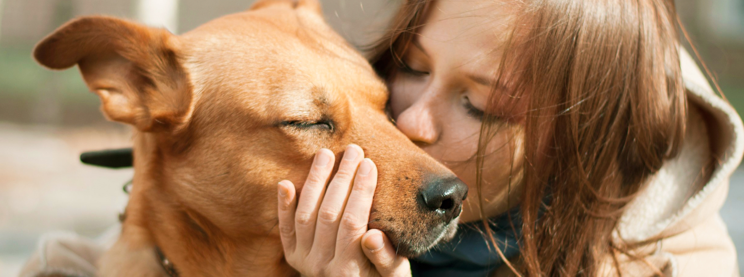Eine Frau gibt ihrem Hund einen Kuss.