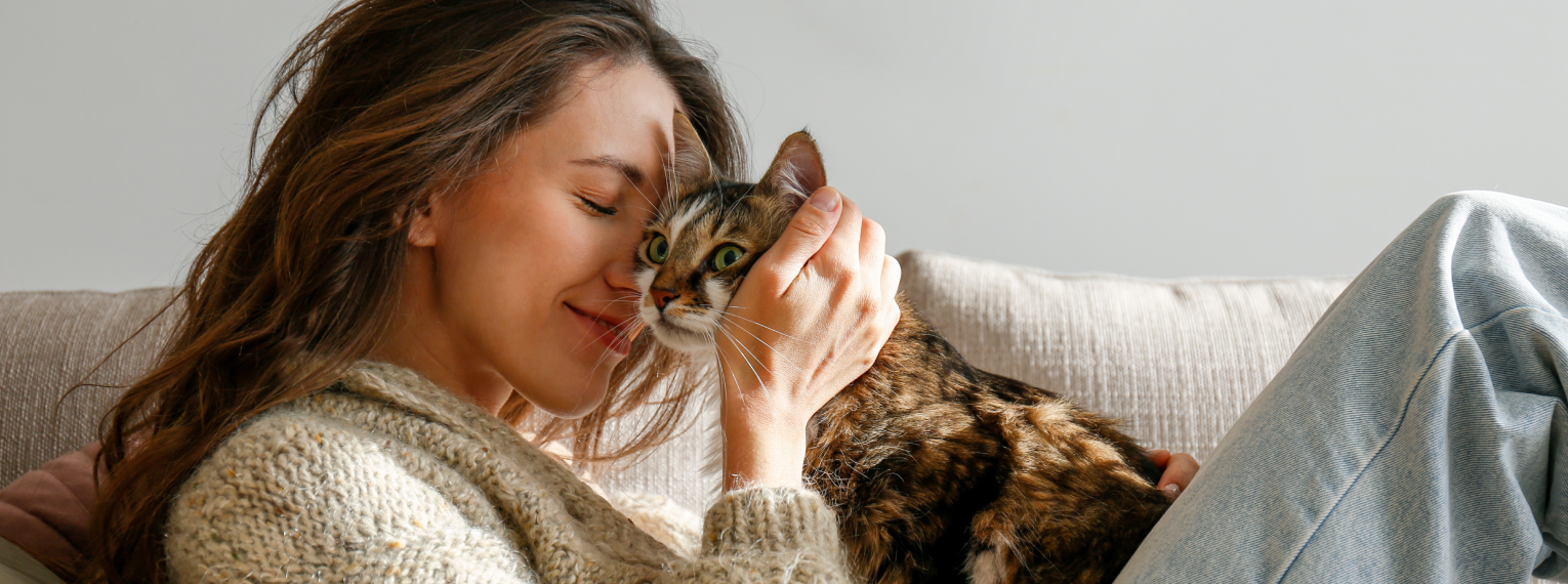 Eine Frau schmust mit ihrer Katze auf dem Sofa.