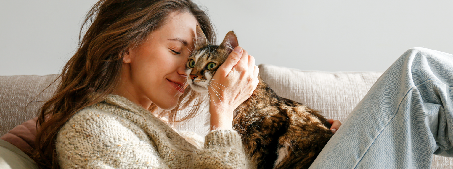 Eine Frau auf einem Sofa schmust mit ihrer Katze.