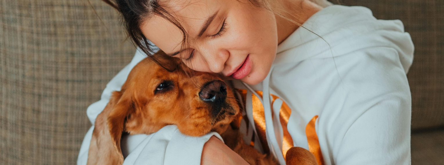 Ein Frauchen hält ihren kranken Hund mit Cushing-Syndrom in den Armen.