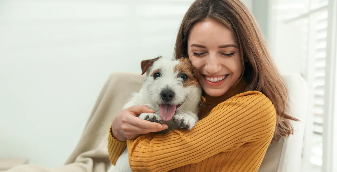 Eine Besitzerin kuschelt mit ihrem Hund.