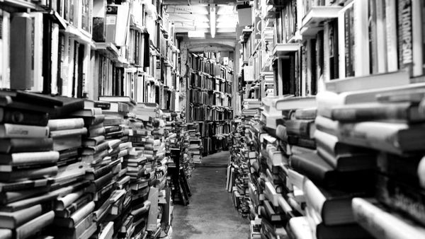 A narrow aisle of books and bookshelves in a library or bookstore.