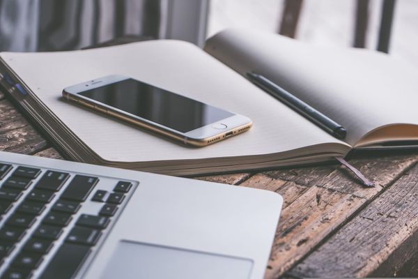 computer and phone and notepad on a desk