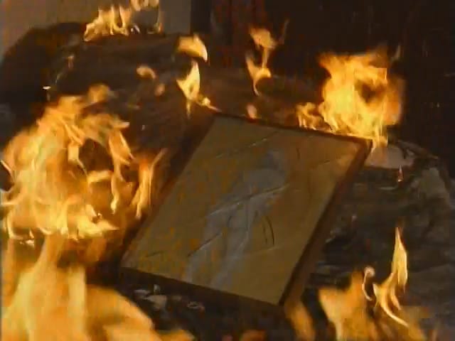 a shattered framed painting of a woman burns