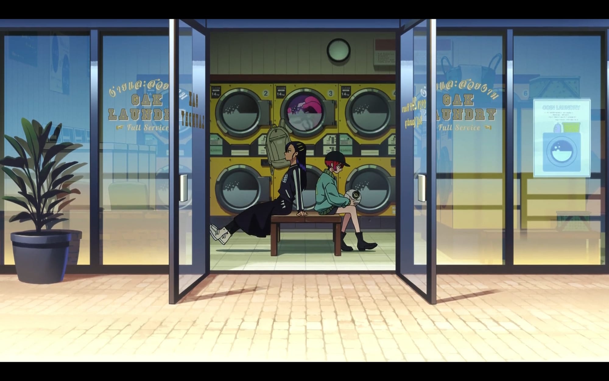nyaan and machu sit at a laundromat in civilian clothes.