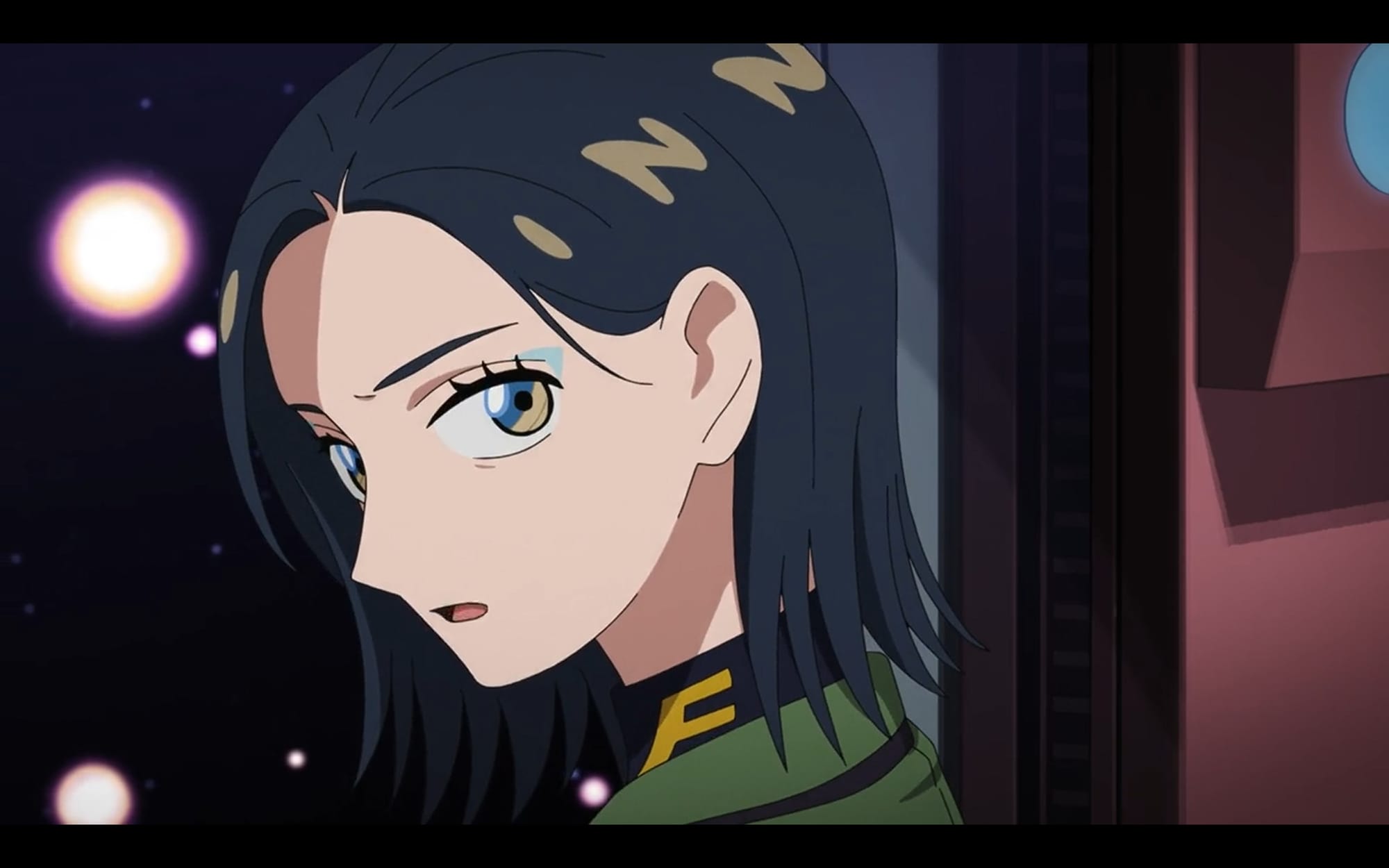 comoli speaks while space behind her is dotted with explosions