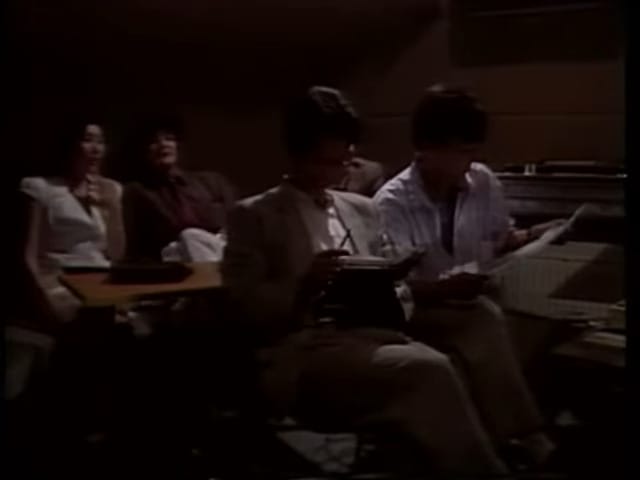 various men and women sit outside the recording booth.