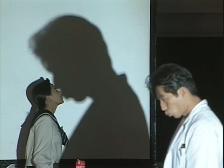 teacher hamura stands in front of a projector so that his shadow "kisses" his student, mayu