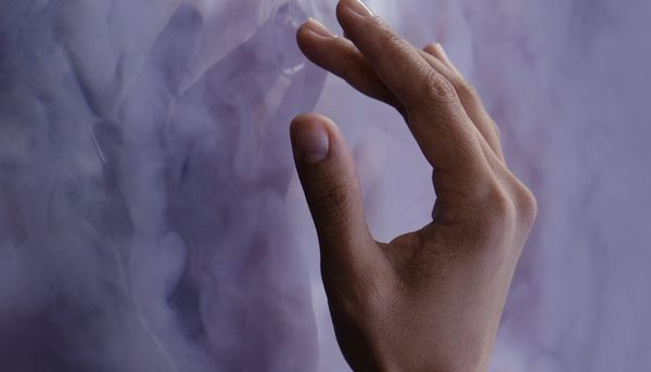 Close-up image of a hand touching a cloudy purple surface
