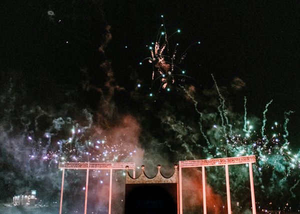 The crowned scoreboard of Kauffman Stadium at night, surrounded by smoke and bursting red and green fireworks.