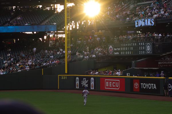 Mets outfielder Juan Soto jogs toward the warning track in left field at T-Mobile Park with the sun shining brightly through the stands above him.
