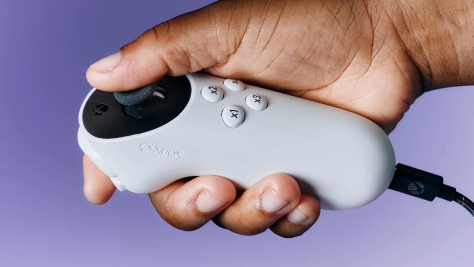 An image of the Xbox Adaptive Joystick being held.
