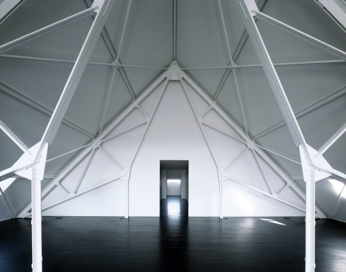 Attic room with exposed white roof trusses and a dark doorway in the Water Pumping Plant Renovation.