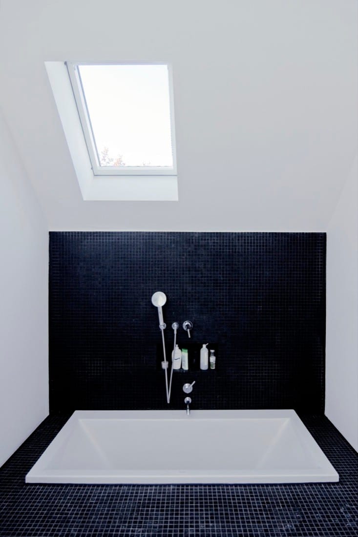 Bathroom detail with black wall, white bath platform and skylight.