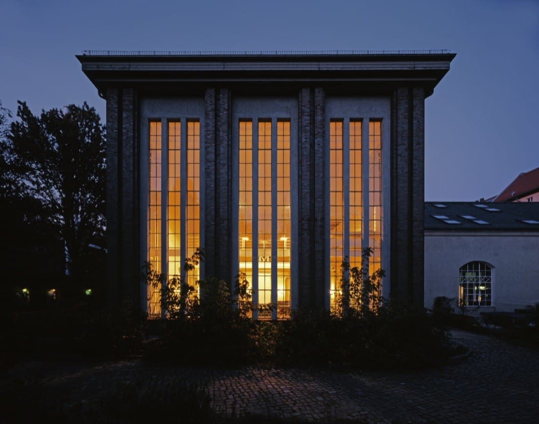 Night exterior of the former water pumping station with tall illuminated windows.