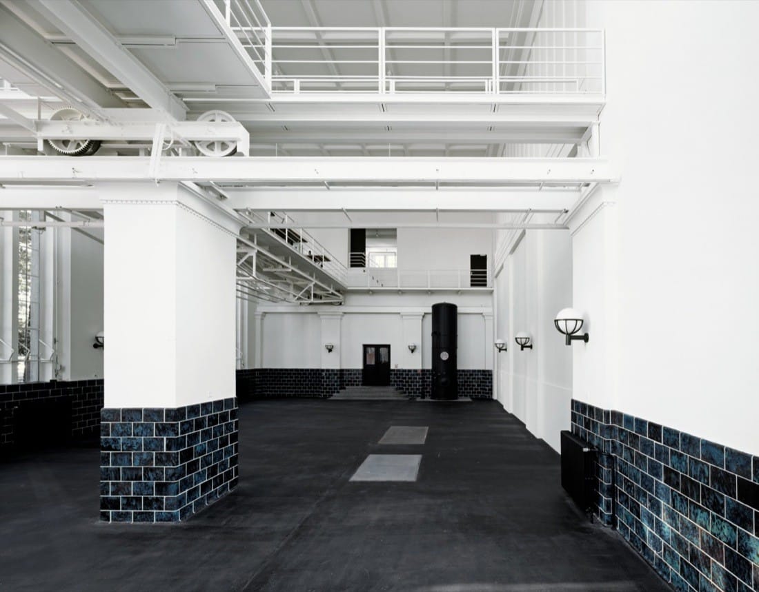 Interior hall with retained dark wall tiles and white structural insertions.