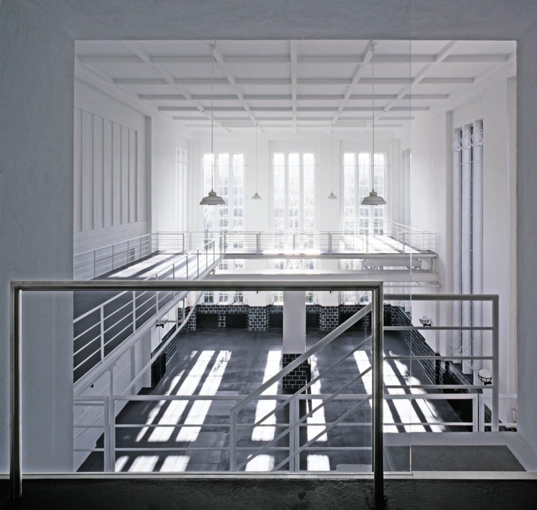 View across a raised platform and railings toward the bright white studio hall.