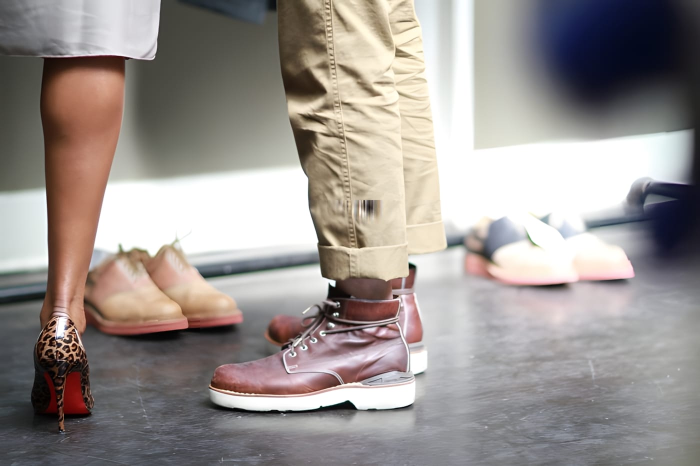 Floor-level view of attendees' footwear at the Visvim LA trunk show — a pair of brown leather Visvim boots with white soles among other shoes.