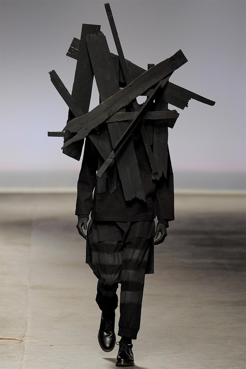 Craig Green FW2013 MAN look 18 — final look: dichromatic paired figures in white and black layered cotton with wooden plank headwear