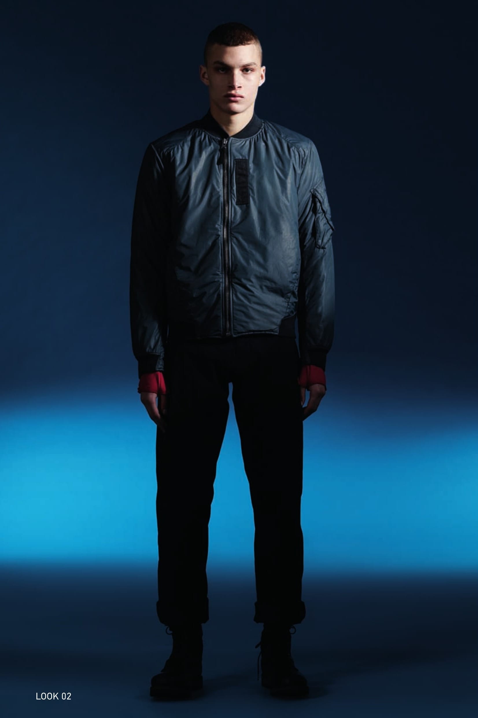 40515 BOMBER JACKET_SOLO-R WITH THERMAL INSULATION Bomber Jacket in SOLO-R, a lightweight and compressible semi-transparent fabric. Its dimpled appearance and unusual shininess are the result of the lamination of the outer fabric with the internal imperceptible breathable, water and wind resistant performance membrane. The Stone Island garment dyeing technology bestows the SOLO-R garments with multi-dimensional colours. On the front, from the sleeves to the bottom, two diagonal cuts held by tape and snap, protect the underlying pockets. On the chest, vertical Cordura® tape appliqué. Armholes engineered for maximum freedom of movement. On the sleeve, a triangular zippered patch pocket, fastened by a rectangular flap with Velcro® which also protects a second pocket. Ribbed collar. Shaped ribbed cuffs and bottom hem. The inside is lined with a technical nylon mesh, quilted with a star pattern with a fine polyester padding substrate, which guarantees the heat insulation of the garment. Slightly off-centre metal zip fastening. 20314 LS UNDERSHIRT_JERSEY MAKO’ Long-sleeve T-shirt in Mako cotton interlock. Garment dyed. Double-needle stitching. Ergonomic sleeves with integrated fingerless gloves. Ribbed neck. Side stitching shifted towards the front. Central stitching on the back. 30110 WIDE PLEATED PANT_CO DIAGONAL Trousers with single dart in diagonal weave comfort cotton. Garment dyed. Wide fit. Diagonal side pockets. Two flat pockets on the back. Zip fly and button at the waist.