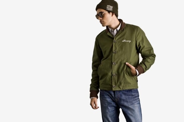 Model in an olive Stussy Japan Fall 2011 snap-front jacket, black beanie and sunglasses.