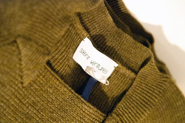 Close-up of a Silent Ventures label pinned inside olive knitwear.
