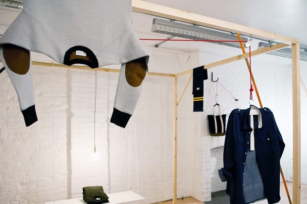 Silent Ventures sweatshirt and navy coat suspended inside the pop-up store's timber display frame.