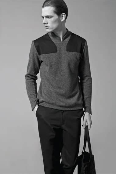Full view of a grey Stahl Corporation knit with black shoulder panels and black trousers.