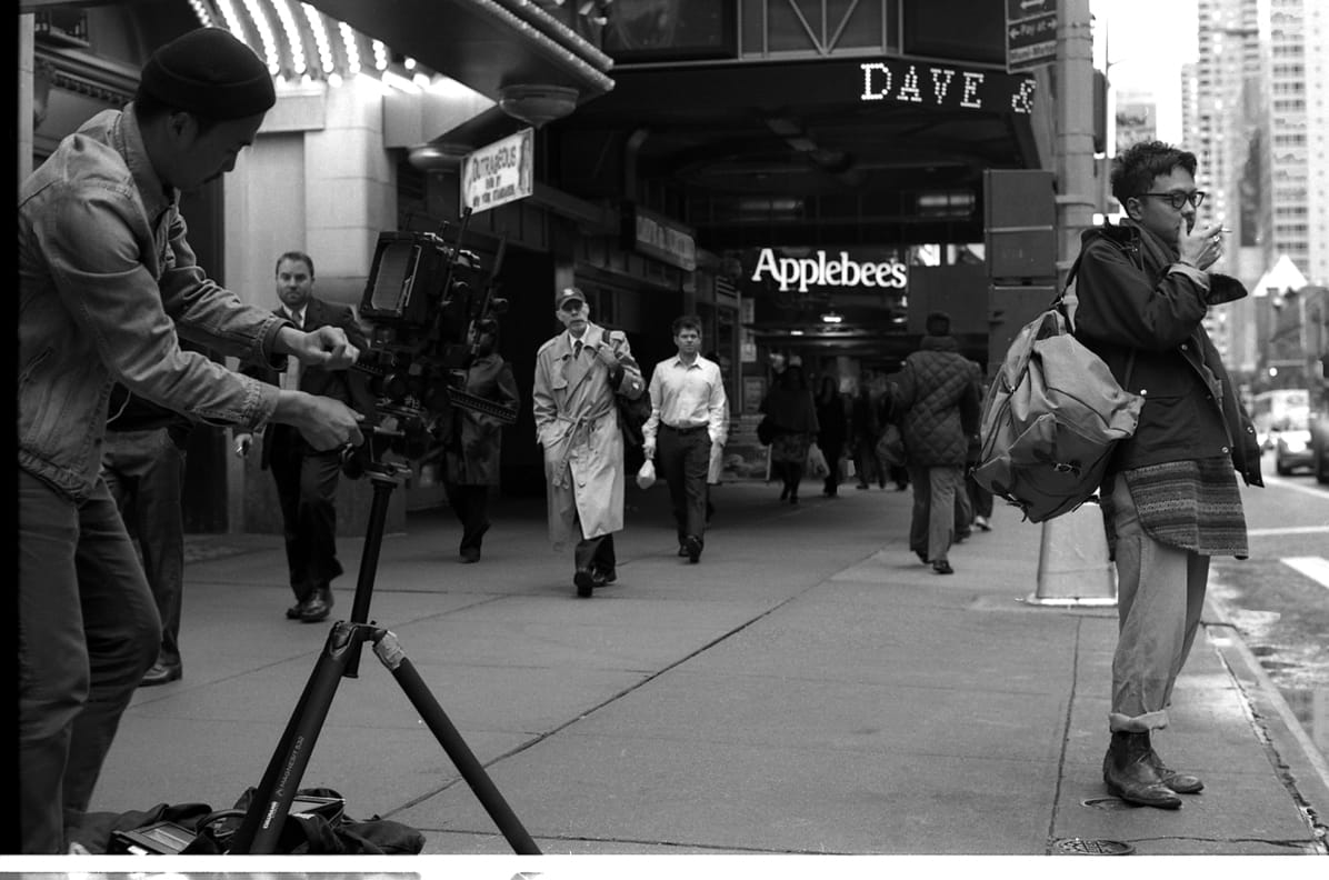 Camera crew filming a layered Nepenthes look outside a Times Square theater.