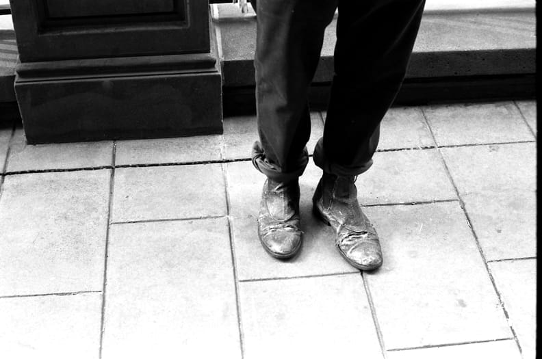 Close view of cuffed trousers and worn leather boots during the Times Square Redux shoot.