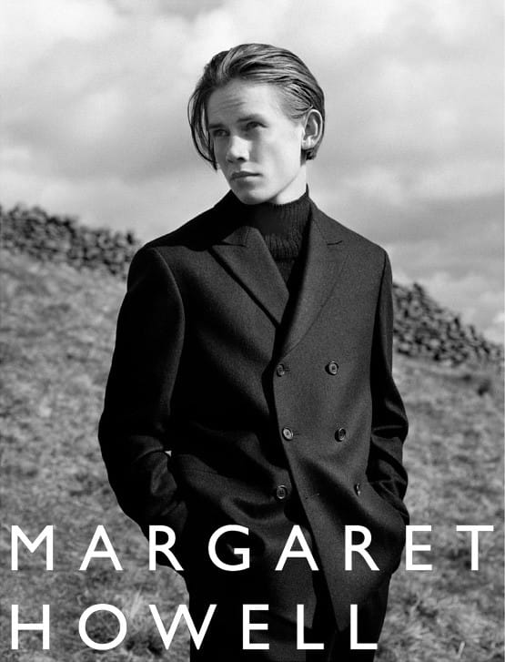 Gustav Frich wearing a black double-breasted Margaret Howell suit in a dry-stone landscape.
