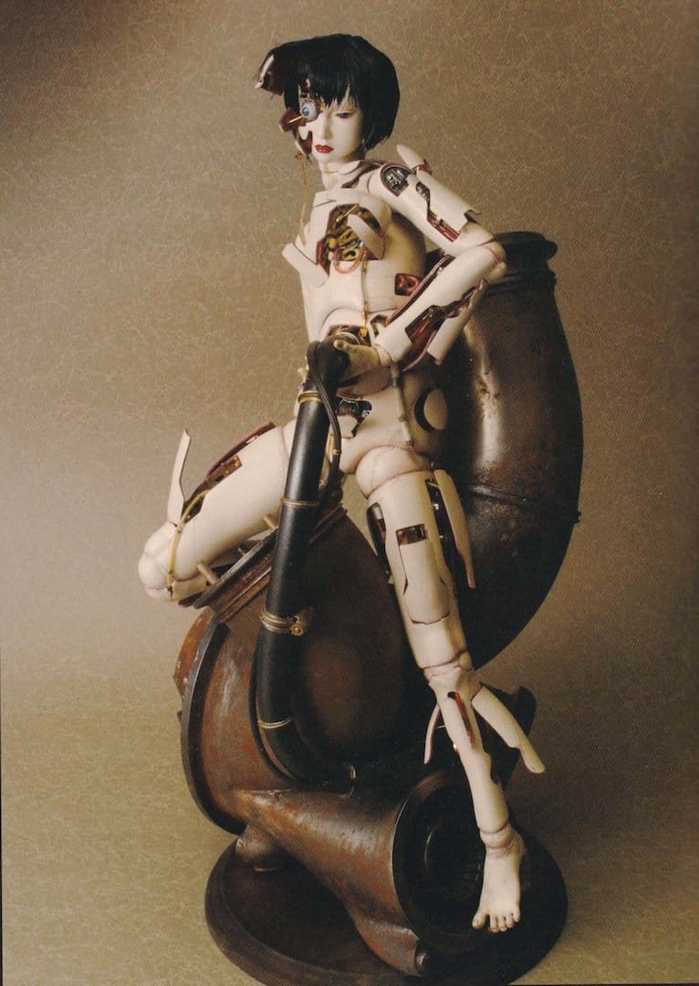 Three-quarter view of the Ghost in the Shell: Innocence Gynoid model seated on a rounded mechanical base.