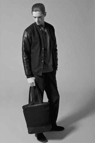 Johannes Niermann carrying a black tote in a black varsity jacket with leather sleeves.